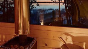 A wood-burning stove with a view of a lake and trees through a window. - Beautiful home in Miedzyzdroje with sauna (Miedzyzdroje)