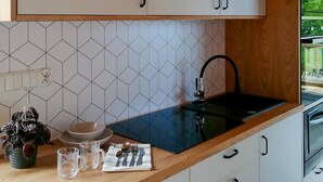 A kitchen with white cabinets, a black sink, and a tiled backsplash. - Beautiful home in Miedzyzdroje with sauna (Miedzyzdroje)