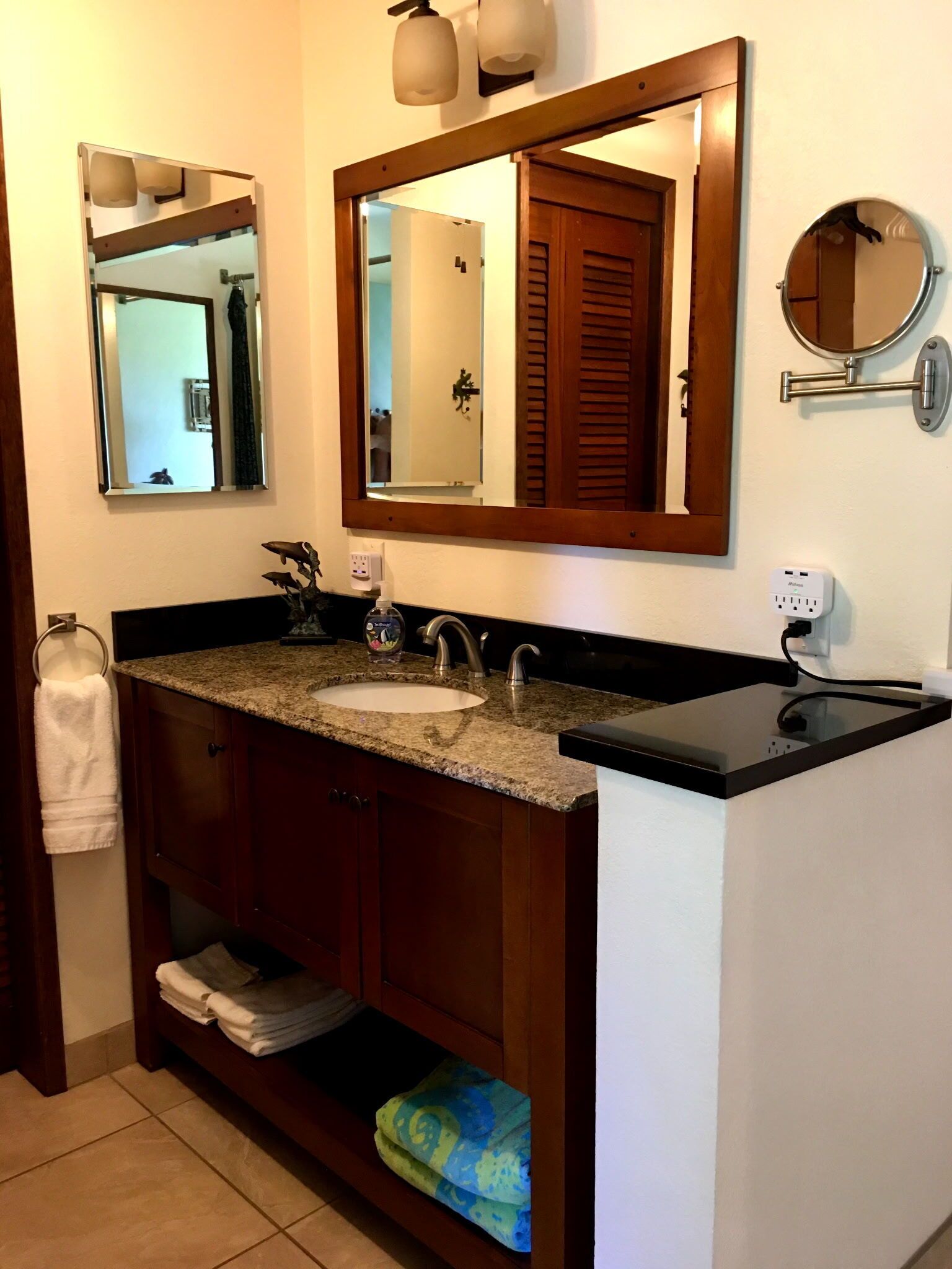 Un baño con lavamanos, espejo, toallero y una toalla en el suelo.