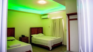 Une chambre d’hôtel avec deux lits, une tête de lit en bois, une table de chevet avec un téléphone et un appareil de climatisation fixé au mur.