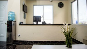 Un espace d’accueil comprenant un distributeur d’eau, une horloge et une plante en pot.