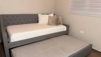 A single bed with a grey headboard and a lower platform bed.