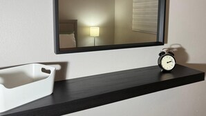 Ein Badezimmer mit weißem Waschbecken, einem Spiegel, einer Uhr und einem Deckenventilator.