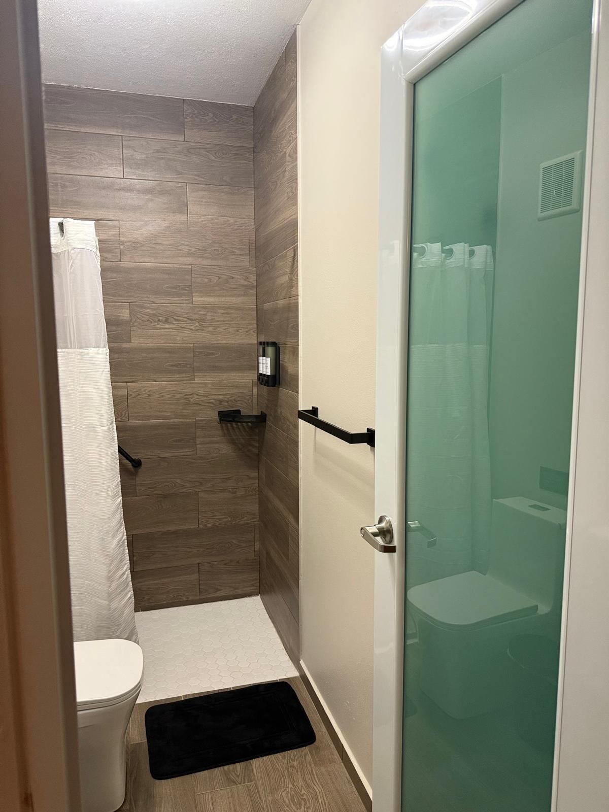 A compact bathroom with a shower, toilet, and a glass-enclosed shower stall.