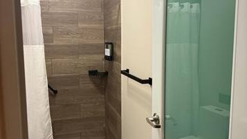 A compact bathroom with a shower, toilet, and a glass-enclosed shower stall.