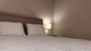 Ein ordentlich bezogenes Bett mit einem geometrisch gemusterten Überwurf, zwei Kissen und einer Nachttischlampe.