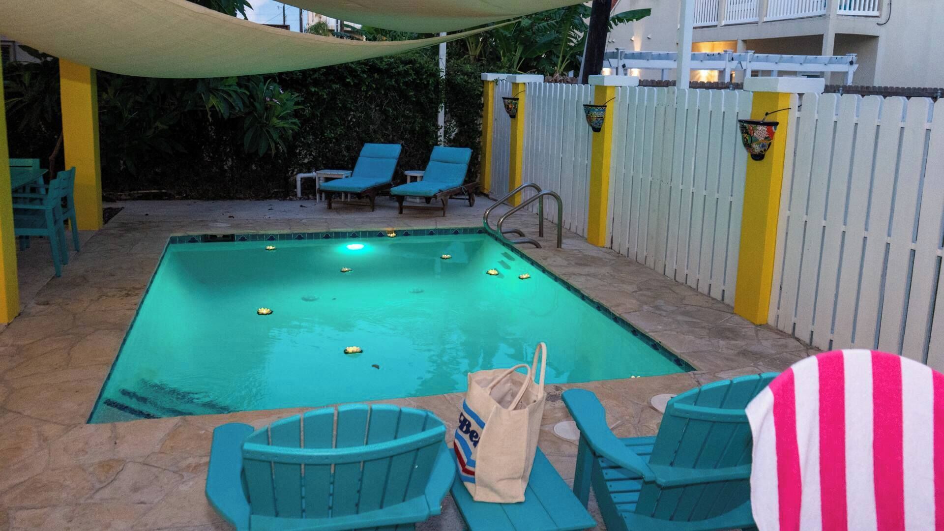 Una piscina con sillas de descanso y una zona con sombra.
