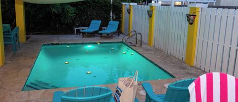 Una piscina con sillas de descanso y una zona con sombra.