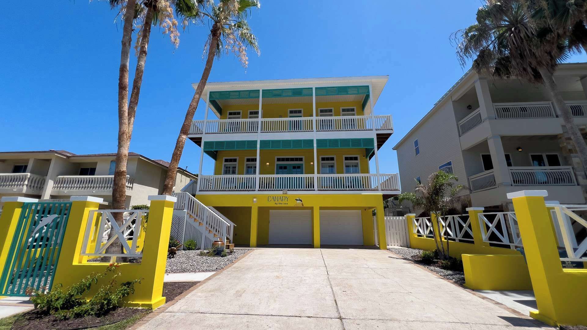Un hôtel à plusieurs étages, doté d’une façade jaune et blanche, de balcons et d’une entrée fermée par un portail.