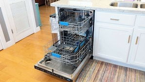 Une cuisine équipée d’un lave-vaisselle, avec des meubles blancs et un tapis à rayures.