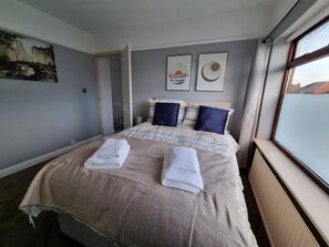 A hotel room with a large bed, two pillows, a blanket, and a window with a view. - 3 Bed Spacious House With Parking (Manchester)