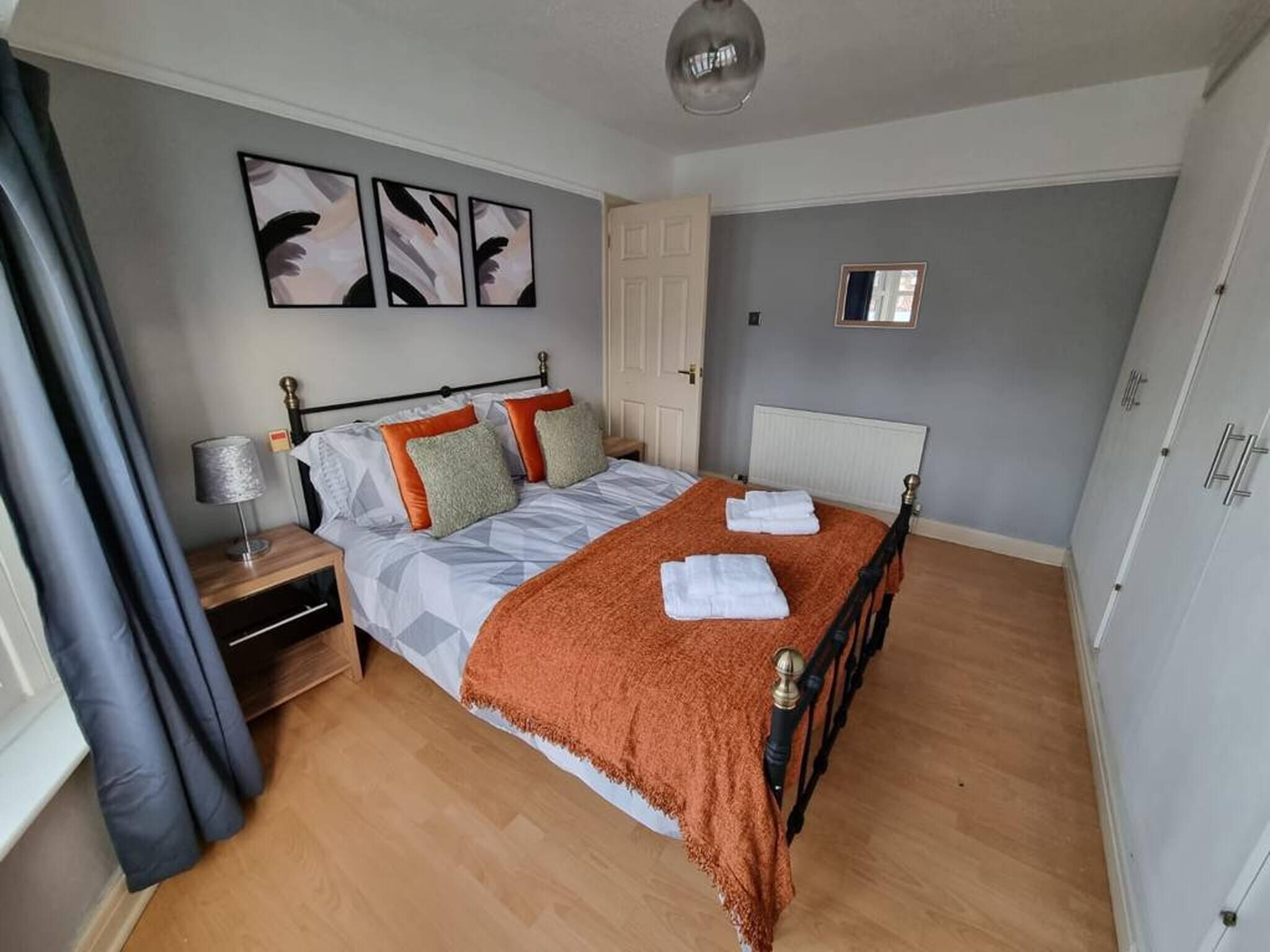 A neatly arranged bedroom with a bed, nightstand, and a mirror.