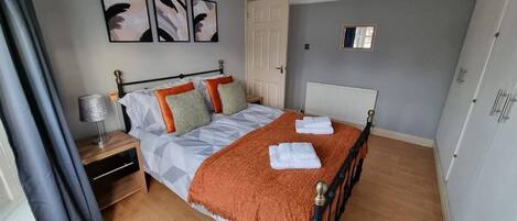 A neatly arranged bedroom with a bed, nightstand, and a mirror.