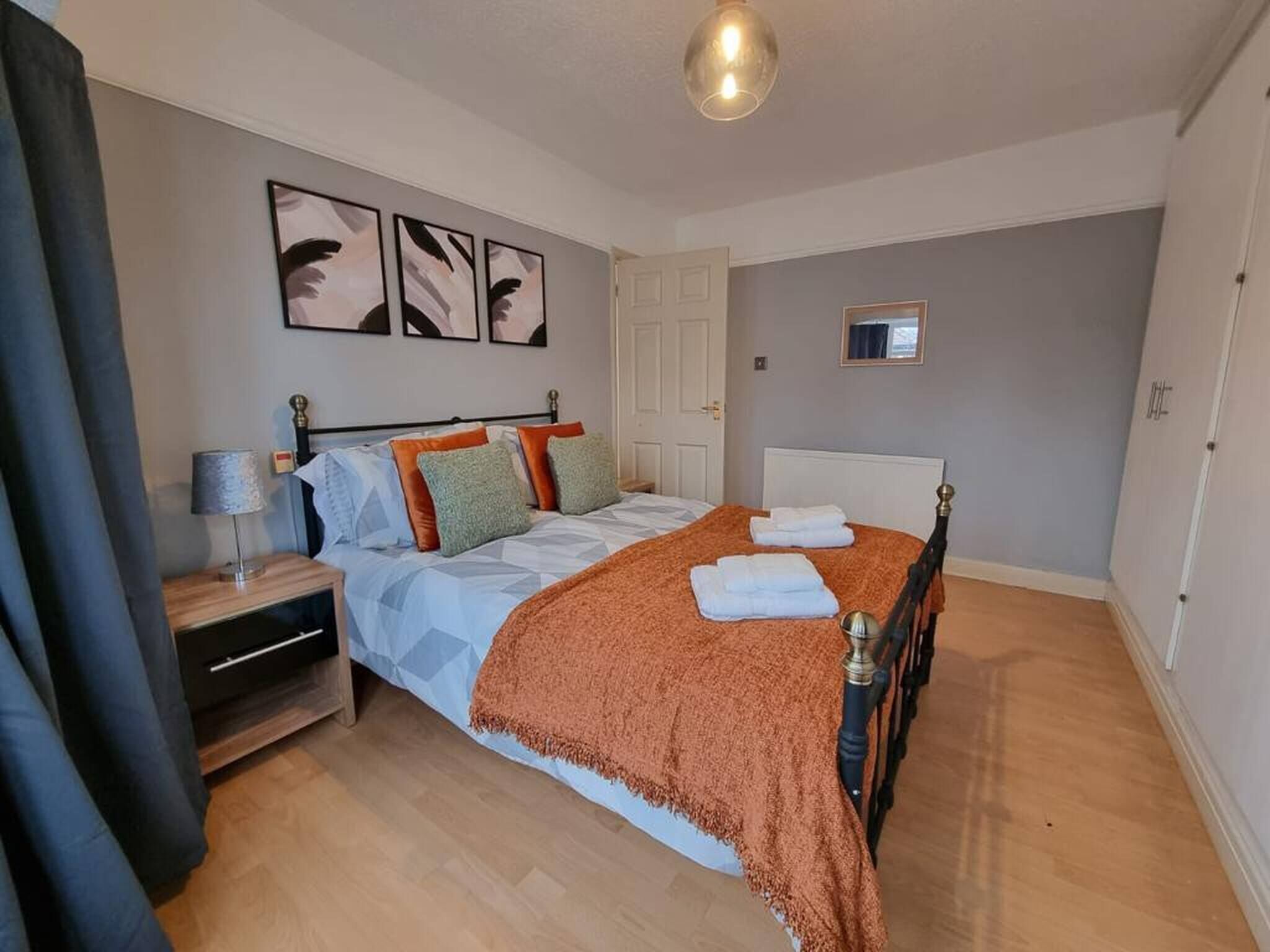 Ein Schlafzimmer mit Bett, Nachttisch, Lampe und einem Kunstwerk an der Wand.