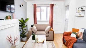 Ett modernt vardagsrum med en beige soffa, en grå soffa, ett soffbord och en tv som är monterad på väggen.