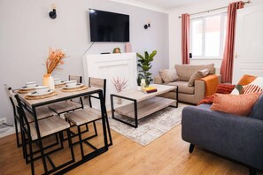 Un salon moderne avec une table à manger, un canapé et un téléviseur.