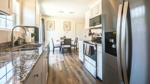 A modern kitchen with granite countertops, stainless steel appliances, and a dining area with a table and chairs.
