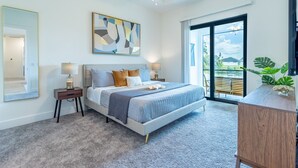 Un dormitorio con cama, mesitas de noche, ventilador de techo, un ventanal y vistas al exterior.