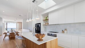 Een moderne keuken met een centraal eiland, witte kasten en uitzicht naar buiten.