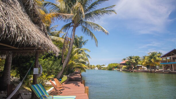 A wooden dock with lounge chairs and a thatched roof structure. - Waterfront tranquility: 3 Iguanas Villa- 1st floor Hibiscus Suite w rooftop pool (Placencia)