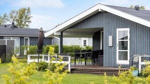 Une maison moderne dotée d’un patio couvert, d’un coin repas et d’un petit jardin.