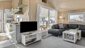 Un salon moderne doté d’un téléviseur à écran plat, d’un canapé, d’une table basse et d’un coin repas avec des chaises et une table.