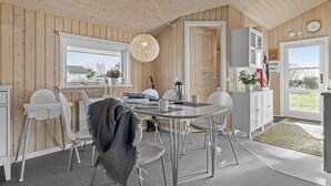 Une cuisine moderne avec des murs en bois, des armoires blanches et un coin repas comprenant une table ronde et des chaises.