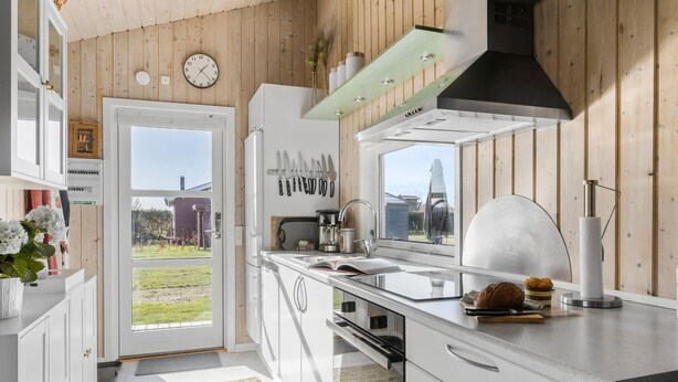 Une cuisine moderne dotée d’une grande fenêtre, de murs en bois et offrant une vue sur un jardin.