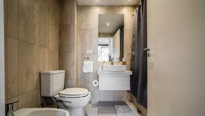 A modern bathroom with a toilet, bidet, sink, and mirror. - FLIPHAUS Malabia 1900 (Buenos Aires)