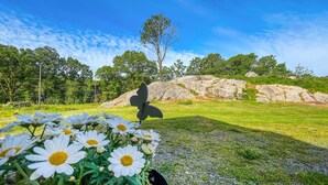 A garden with a rock formation, a clear sky, and a flower arrangement in the foreground. - 3 bedroom cozy home in Farsund (Farsund)