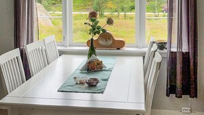 A dining table with a vase of flowers, a bottle, and a bowl. - 3 bedroom cozy home in Farsund (Farsund)