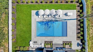Eine Vogelperspektive auf ein Schwimmbecken mit Liegestühlen und einer kleinen Liegefläche.