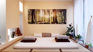 Un dormitorio moderno con una cama grande, un mural temático de bosque y una mesita de noche con una planta.