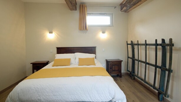 A bedroom with a bed, two bedside tables, a window, and a wooden ladder. - Gîtes de France® - Les Ecuries du Mesnil aux Moines (OSMOY SAINT VALERY)