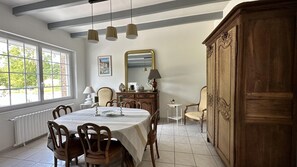Enjoy meals in this elegant dining room with a large round table, wooden chairs, and a beautiful view of the surrounding greenery.