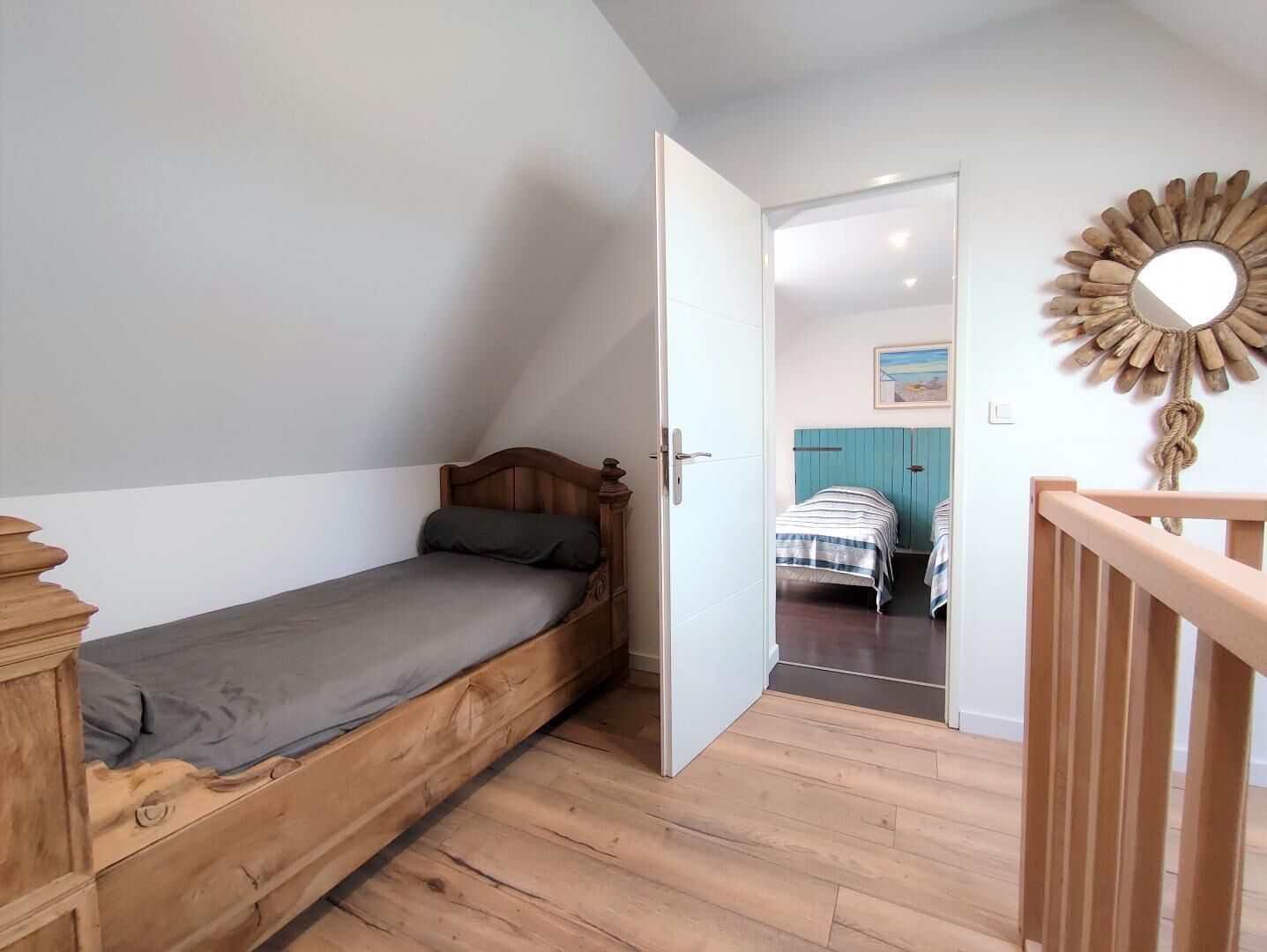 Ein kleines Zimmer mit einem Einzelbett, einem Holzkopfende und Holzboden.