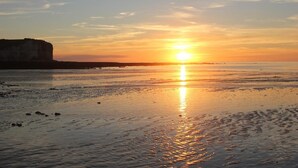 A beach at sunset with a cliff in the background.