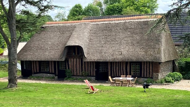 A thatched-roof cottage with a dining area and outdoor seating.