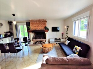 Un salon avec une cheminée, un canapé, un coin repas et un téléviseur.