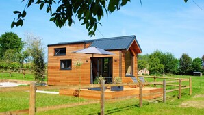 Eine Holzhütte mit einer Terrasse, einem überdachten Sitzbereich und einem umzäunten Garten.