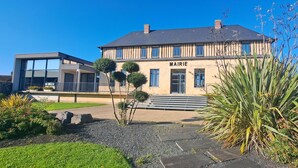 Un edificio moderno con un cartello 'MAIRIE' e un giardino curato con diverse piante.