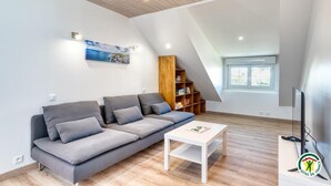Un soggiorno moderno con un divano grigio, un tavolino da caffè bianco e una libreria in legno. Una finestra offre luce naturale ed è presente un quadro appeso al muro.