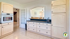 Una cucina con forno a incasso, un grande specchio sopra il piano di lavoro e una porta che dà su un'altra stanza.