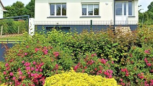 A two-story house with a tiled roof, white exterior walls, and a front garden with pink and yellow flowers. - Gîtes de France® - Between Sea and Earth (BAILLY EN RIVIERE)