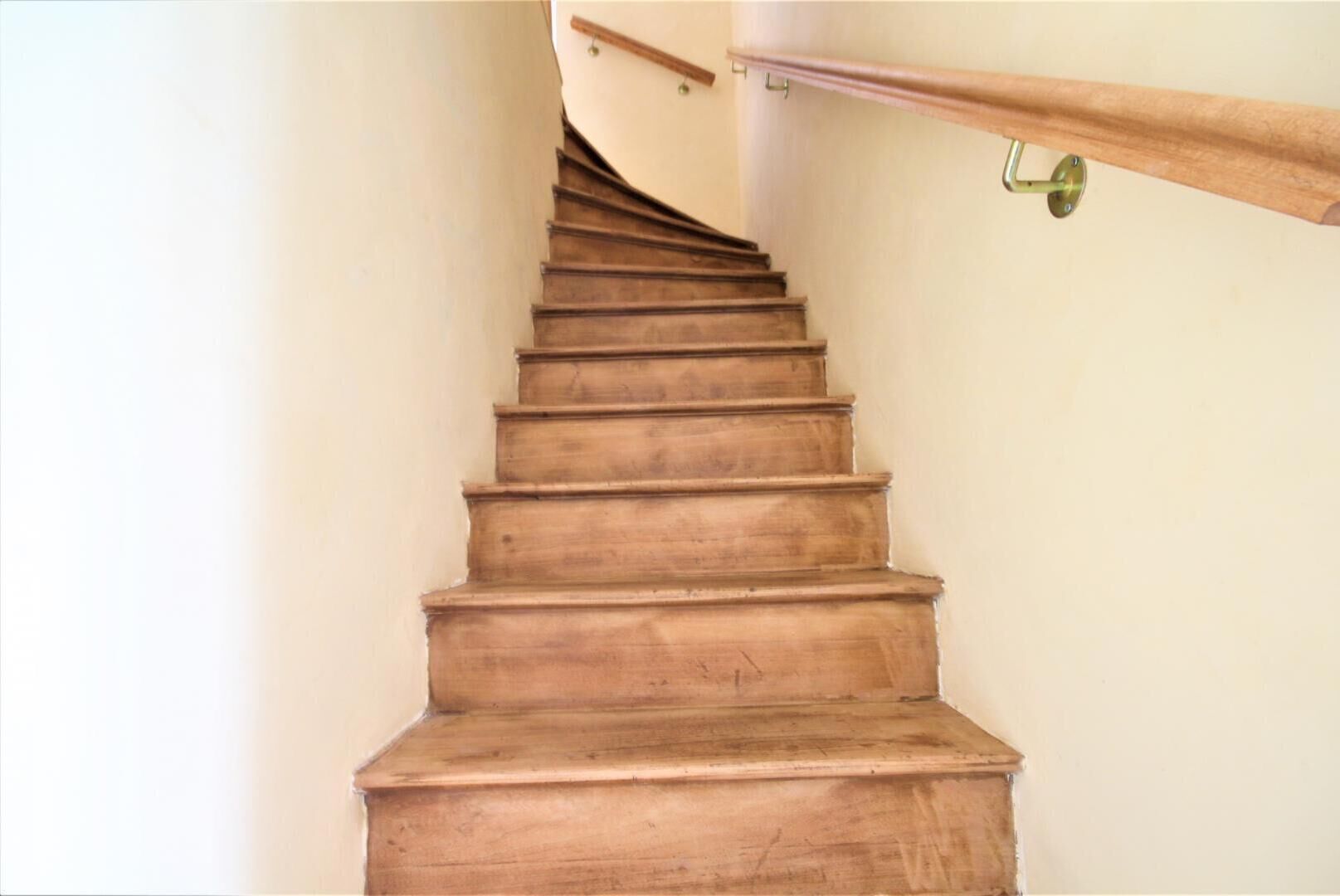 Una escalera de madera con barandilla a la derecha.