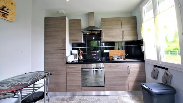 A modern kitchen with wooden cabinets, a stainless steel oven, and a coffee maker. - Gîtes de France® - Between Sea and Earth (BAILLY EN RIVIERE)
