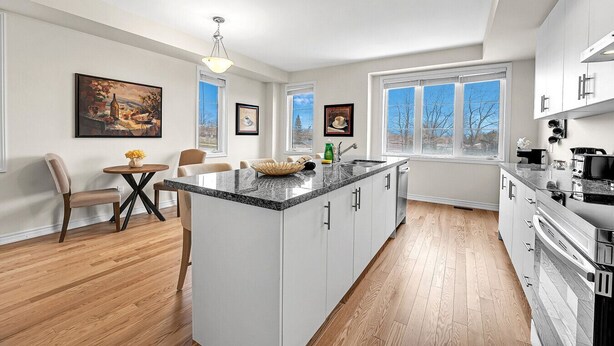 A modern kitchen with a central island, white cabinetry, and a dining area with a table and chairs.