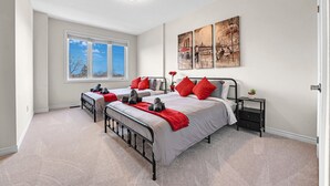 A bedroom with two beds, a window, and artwork on the wall.