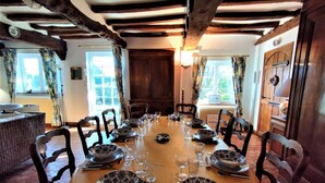 A dining room with a wooden table set for a meal, surrounded by chairs. - Gîtes de France® - La Roselière (SAINTE COLOMBE)