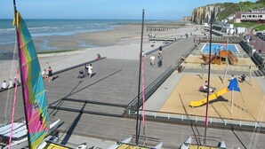 A beachside pier with multiple boats, a sandy beach, and a cliff in the background. - Gîtes de France® - La Roselière (SAINTE COLOMBE)